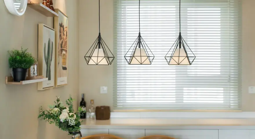 Trzy wiszące lampy w kształcie diamentu nad stołem w salonie.